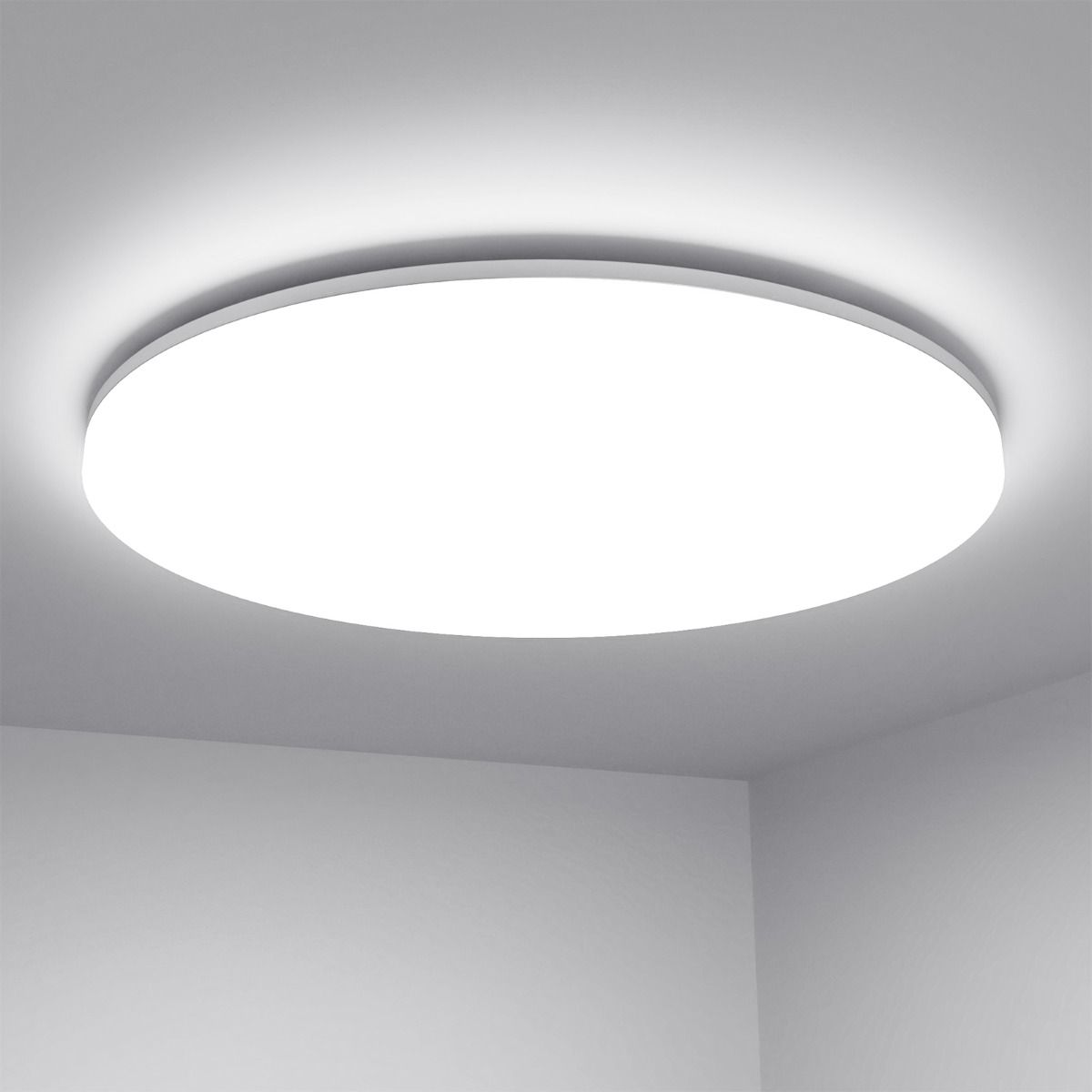 Round flush-mount LED ceiling light installed on a white ceiling, emitting bright, even illumination in a modern minimalist room corner.