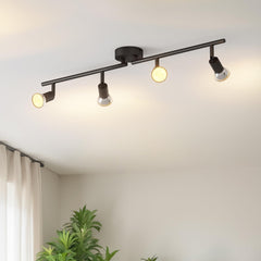 Black ceiling light fixture with four bulbs on a white ceiling, with a plant and curtain in the foreground.