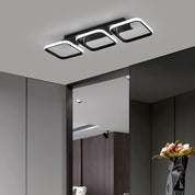 Modern ceiling light fixture in a room with a vase of flowers on a table.