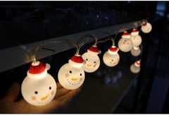 String lights shaped like snowmen with red hats on a dark background