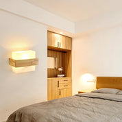 Modern bedroom with wooden wardrobe, bed, and wall lights.