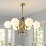 Modern chandelier with gold finish and white glass shades in a room with large windows.