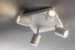 Modern ceiling light fixture with four lights on a gray ceiling.