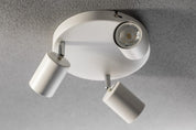 Ceiling light fixture with three white cylindrical lamps on a gray ceiling.