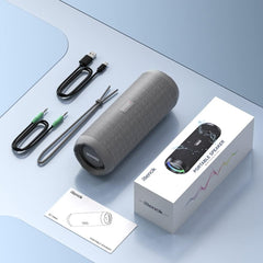 Gray portable speaker with accessories on a light blue surface