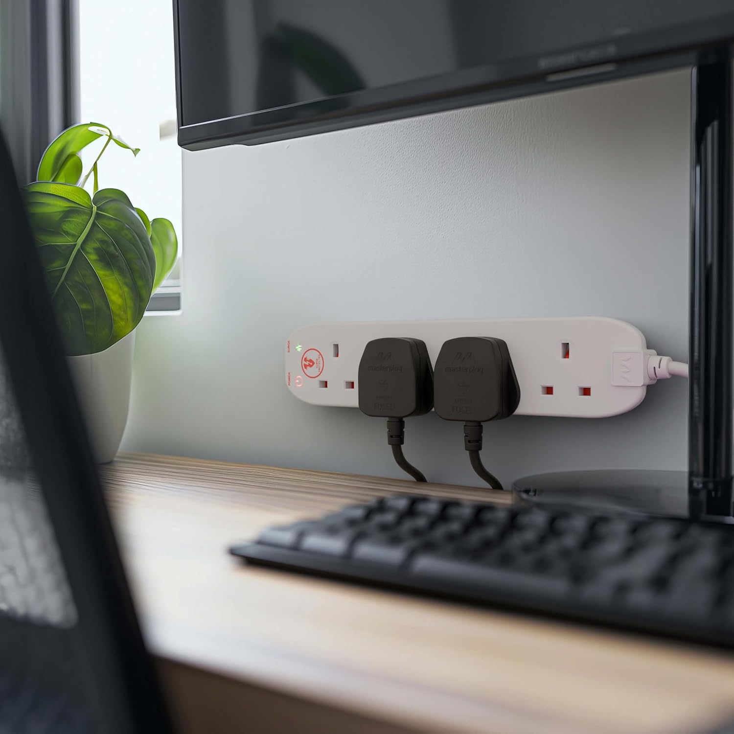 Desk setup with a computer monitor, keyboard, and power strip.
