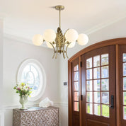 Chandelier hanging in a room with a wooden door and decorative vase.