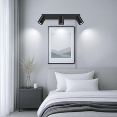 Modern bedroom with black wall lights, framed artwork, and a bed.