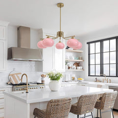 Modern kitchen with pink pendant light, white countertops, and wicker chairs.