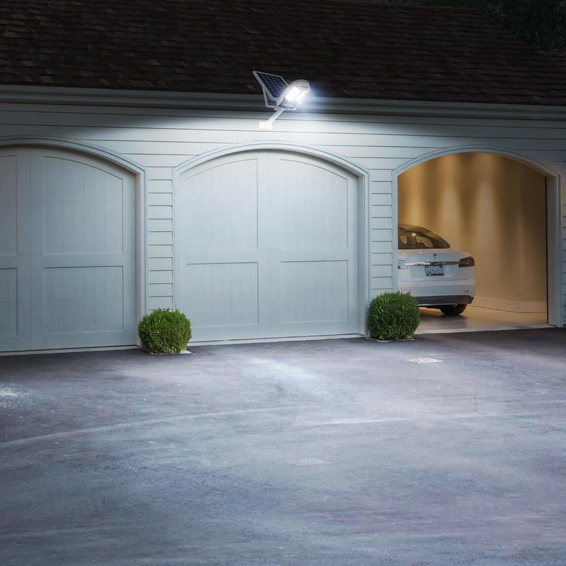 Garage with a car inside, illuminated by a security light on a house exterior.
