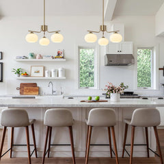 Modern kitchen with white island, stools, and pendant lights.