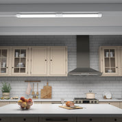 Modern kitchen with white countertops, gray tiled walls, and stainless steel appliances.