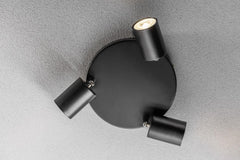 Black ceiling light fixture with three adjustable arms on a gray ceiling.