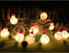 String lights with snowman design on a wooden surface with a bicycle in the background.