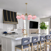 Modern kitchen with pink pendant lights, gray bar stools, and a television mounted on the wall.
