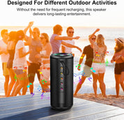 Black portable speaker on a wooden surface with people dancing in the background at the beach.