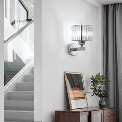 Modern wall sconce on a white wall with a staircase and decorative items in the background.
