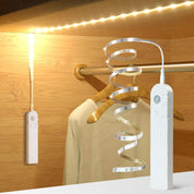 Clothing hanger with LED strip light and remote control on a wooden background