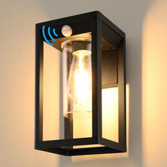 Black outdoor wall light fixture with glass cover and motion sensor on a neutral background