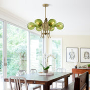 Dining room with a green glass chandelier, wooden table, and chairs.