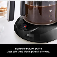 Coffee maker with illuminated on/off switch on a white surface