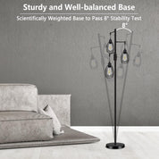Black floor lamp with three glass shades in a room with a gray sofa.