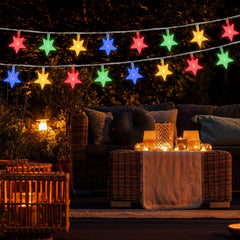 Colorful string lights above a outdoor seating area with a couch and small table.
