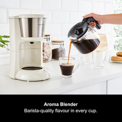 Aroma Blender being used to pour coffee into a glass cup on a kitchen counter.