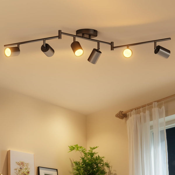 Ceiling light fixture with five lights on a beige ceiling, with a plant and window in the background.