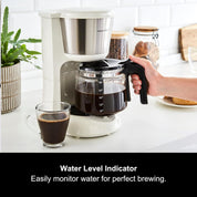 Coffee maker with a glass carafe on a kitchen counter, featuring a water level indicator.