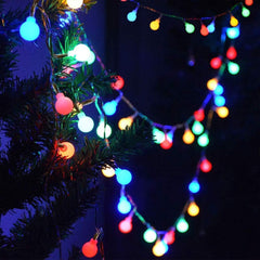Colorful string lights draped over a Christmas tree against a dark background