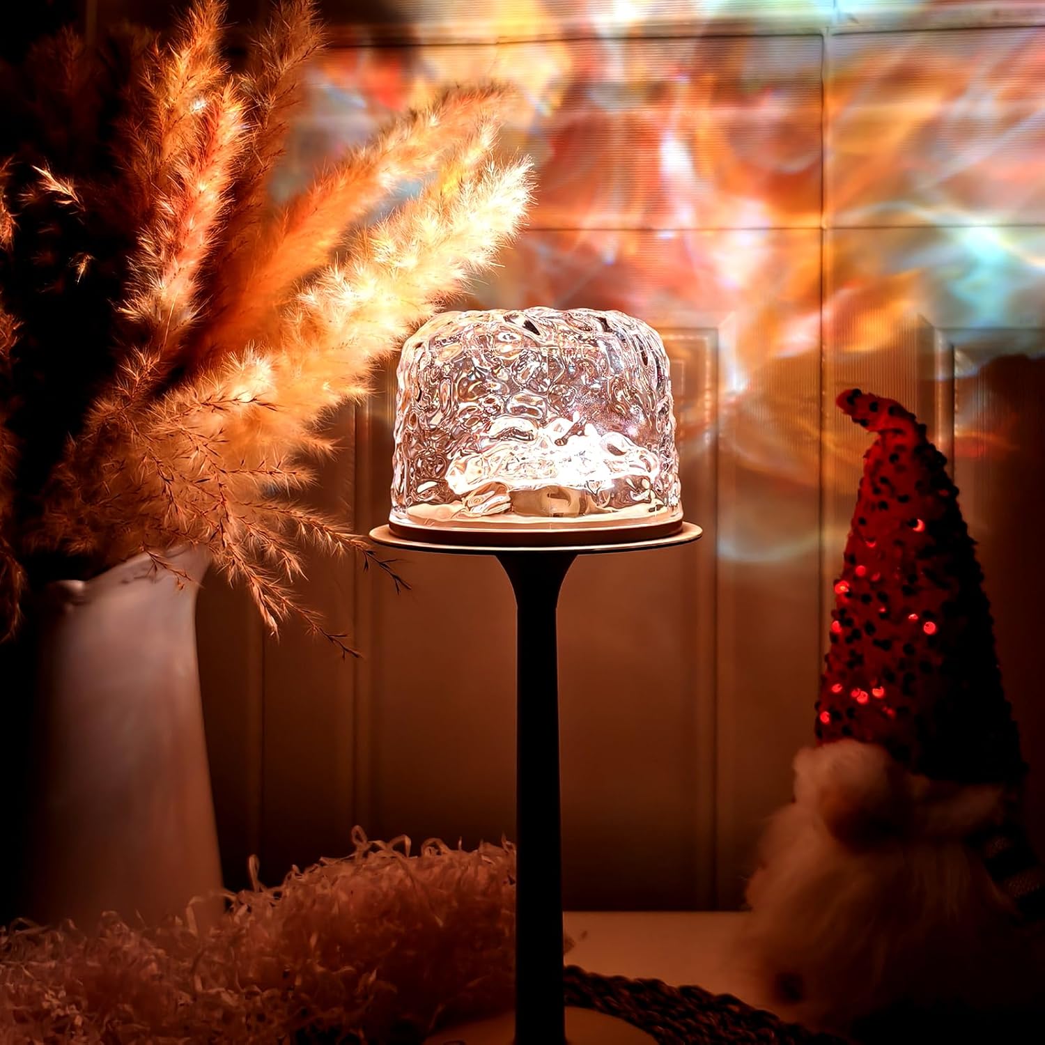 Decorative glass lamp on a stand with pampas grass and colorful lights in the background