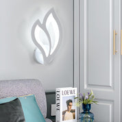 Decorative wall light fixture on a gray wall with a Loewe product and vase in the foreground.