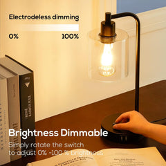 Desk lamp with a hand adjusting the brightness switch, books and an open book in the background.