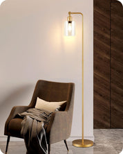 Gold floor lamp next to a brown armchair with a blanket in a room setting.