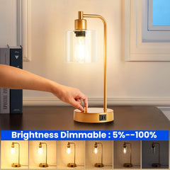 Gold table lamp with a hand adjusting the brightness, set against a neutral background.