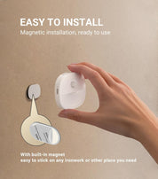Hand holding a magnetic light fixture with text on an beige background