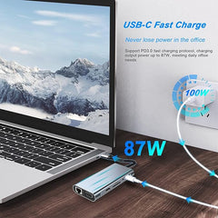 Laptop with USB-C fast charging device on a wooden surface, showing a mountainous landscape on screen.