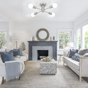 Living room with gray fireplace, white sofa, and modern ceiling light fixture.