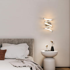 Modern bedroom with a spiral wall light fixture and decorative items on a nightstand.