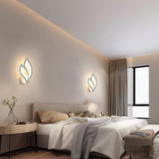 Modern bedroom with leaf-shaped wall lights, bed, and side table.