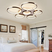 Modern ceiling light fixture in a bedroom setting with a bed, nightstands, and artwork.