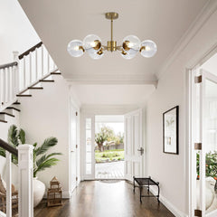 Modern chandelier hanging in a bright living room with white walls and a staircase.