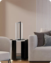 Modern interior with a black cylindrical table and gray sofa against a beige wall.