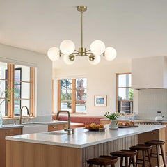 Modern kitchen with a chandelier, sink, and stools.