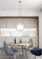 Modern kitchen with round wooden table, chairs, and pendant light fixture.