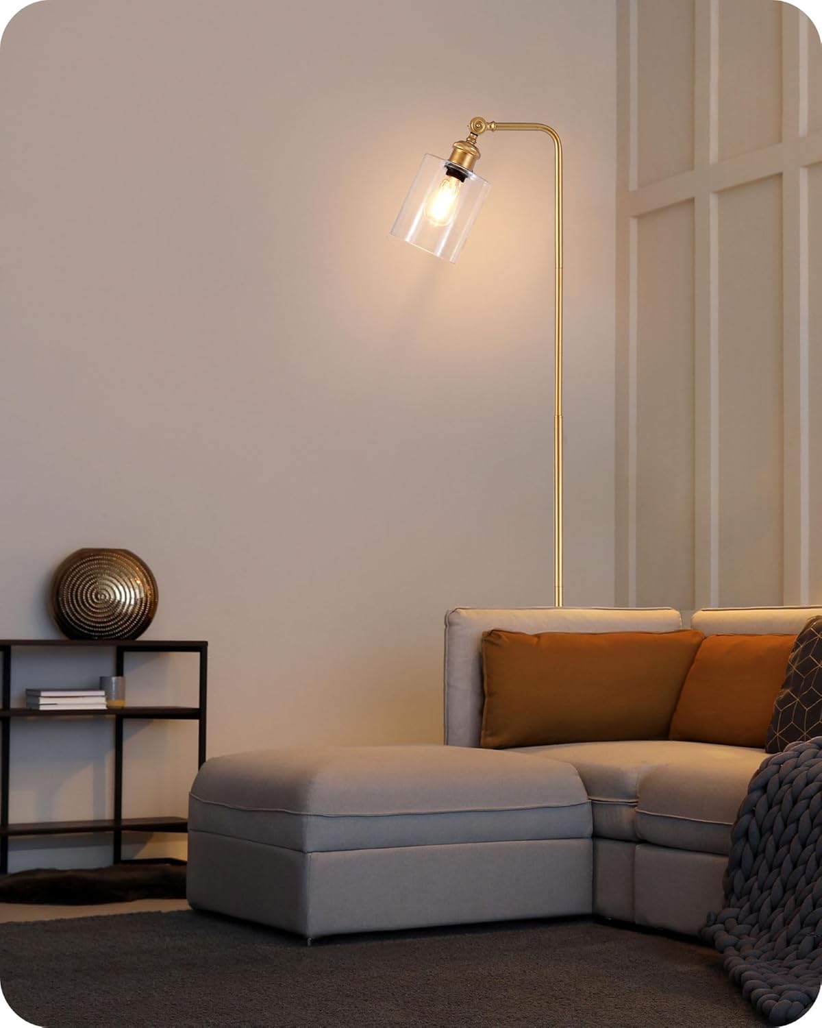 Modern living room with a gray sectional sofa, gold floor lamp, and decorative items.