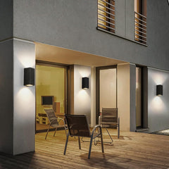 Modern outdoor seating area with chairs and wall lights on a building exterior.