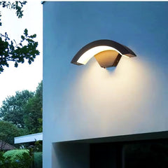 Modern outdoor wall light fixture on a building exterior with trees in the background