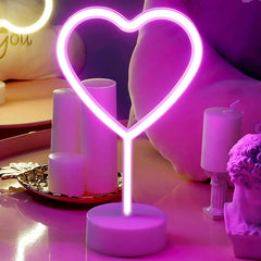 Neon heart-shaped light on a table with candles and decorative items.
